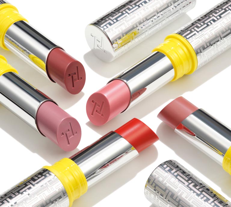 An image of Trinny London's Just Joyous High Shine Lipstick. A few shades of the product are shown in their primary packaging, open so you can see the shades, on a white background.