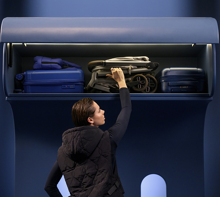 picture of someone putting a pushchair into the overhead locker on a plane