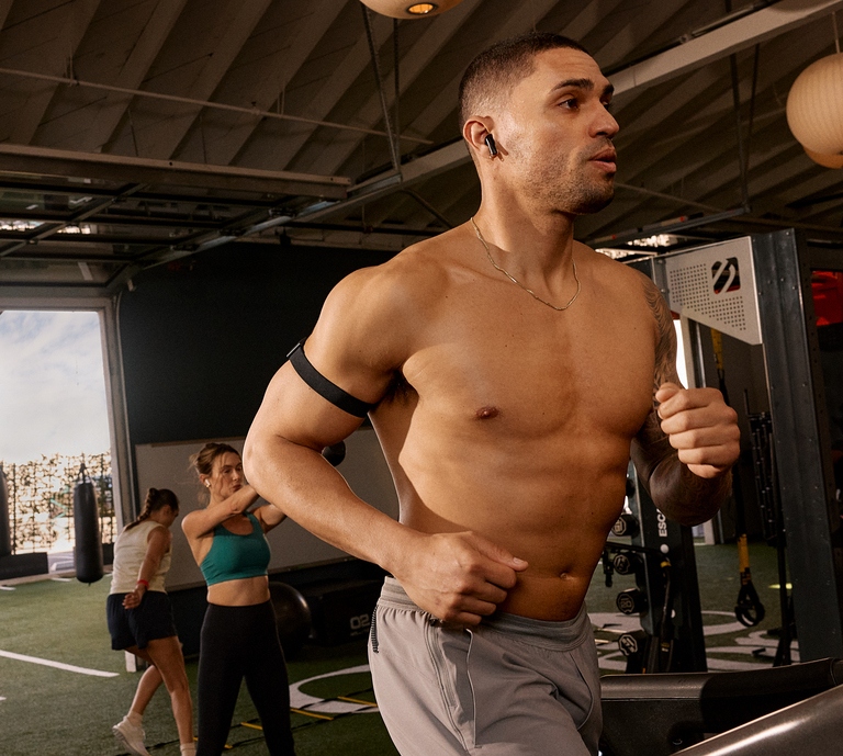 Man running on treadmill with WHOOP bicep band on