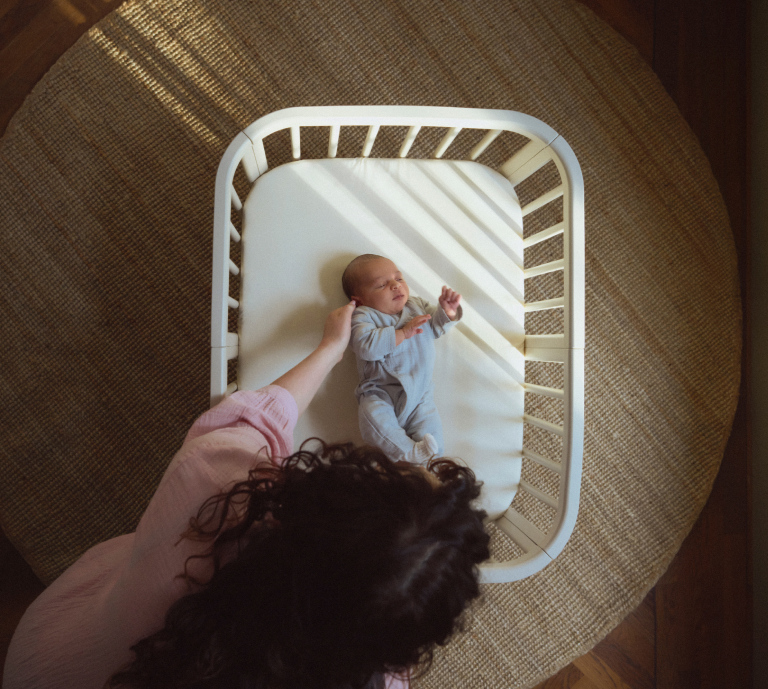 women picking up baby from bed 