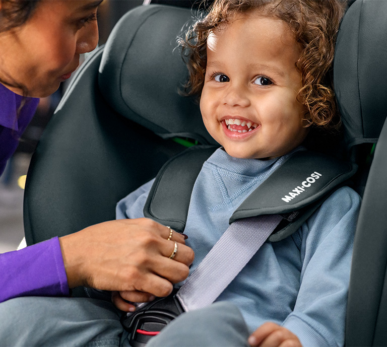 Image of child in Maxi-Cosi Onyx car seat smiling with a mother figure