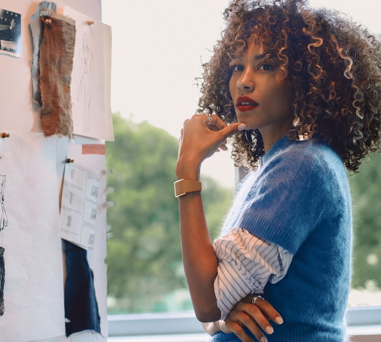 Woman working wearing WHOOP LeatherLuxe brown and gold band