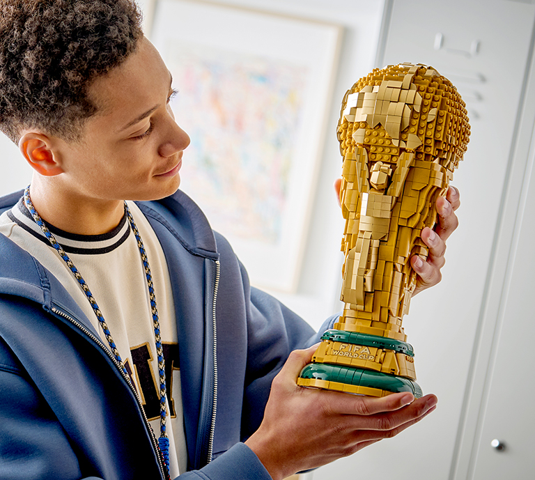 Banner Advertisement for LEGO Editions celebrating the World Cup Kick Off with a person building a product.